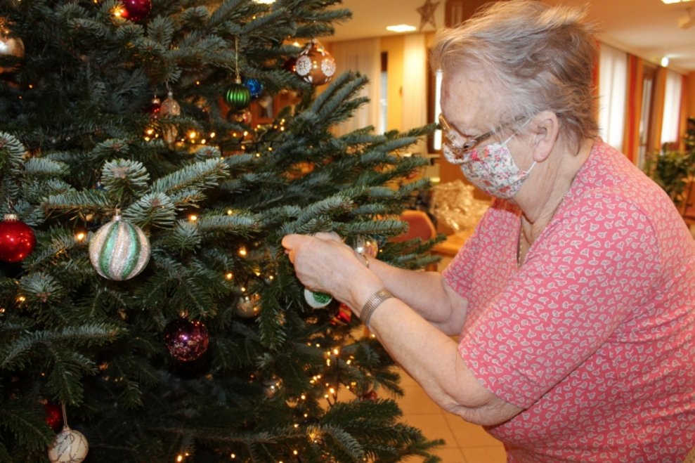 Eine Bewohnerin schmückt den Christbaum.