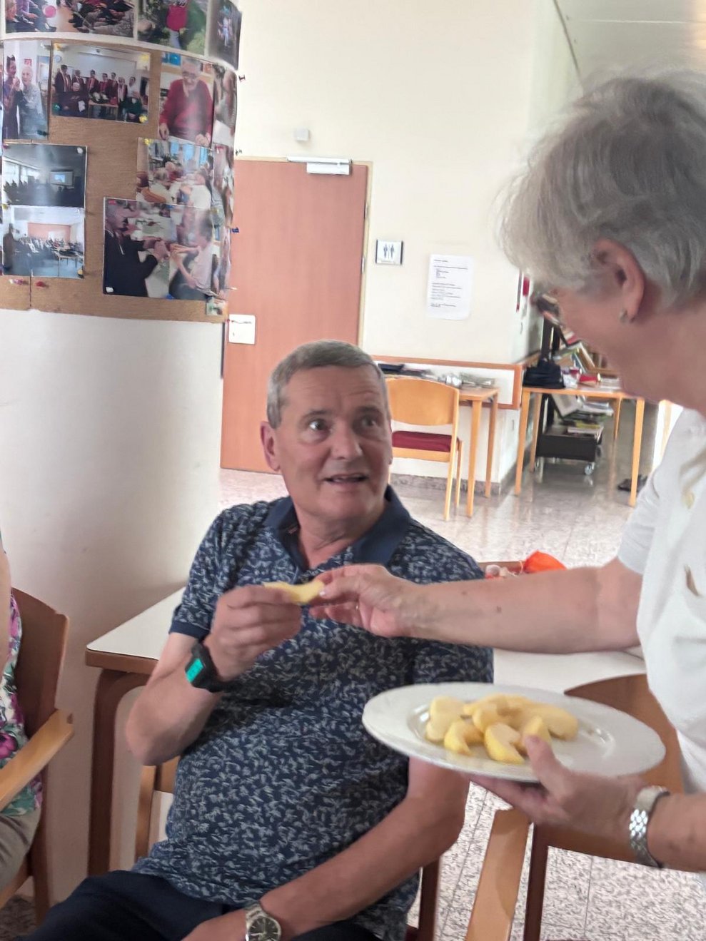 Frau gibt Bewohner eine Apfelspalte in die Hand.
