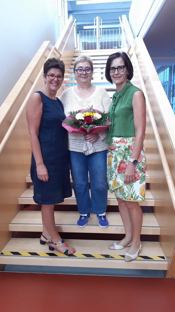 Drei Damen mit einem Blumenstrauß.