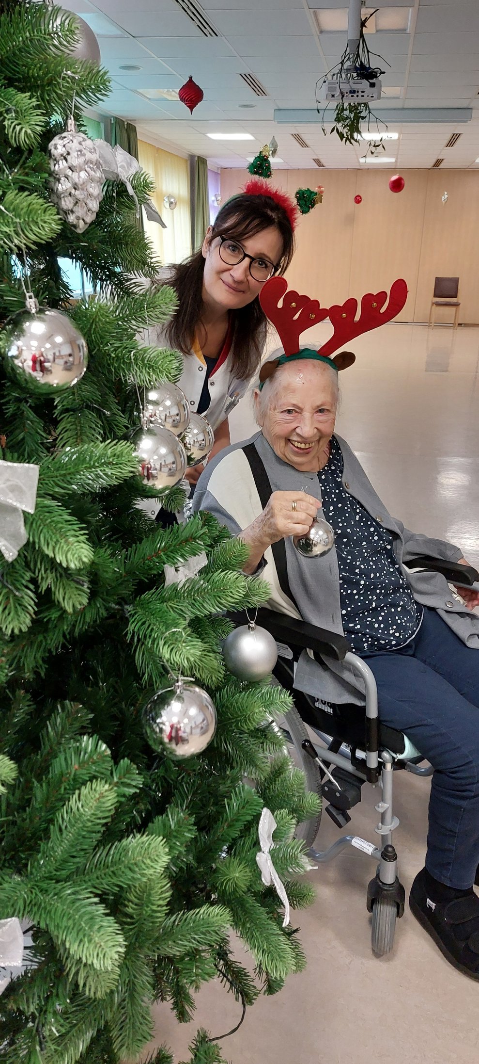Bewohnerin und Mitarbeiterin helfen beim Christbaum schmücken