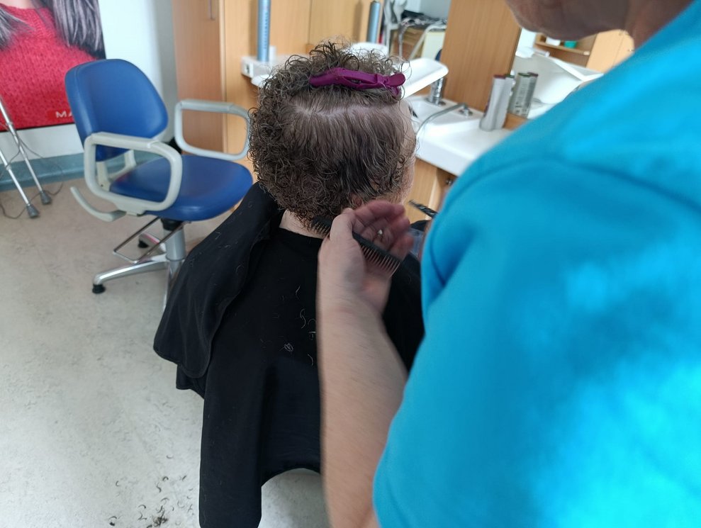 Friseurin schneidet Bewohnerin Haar.
