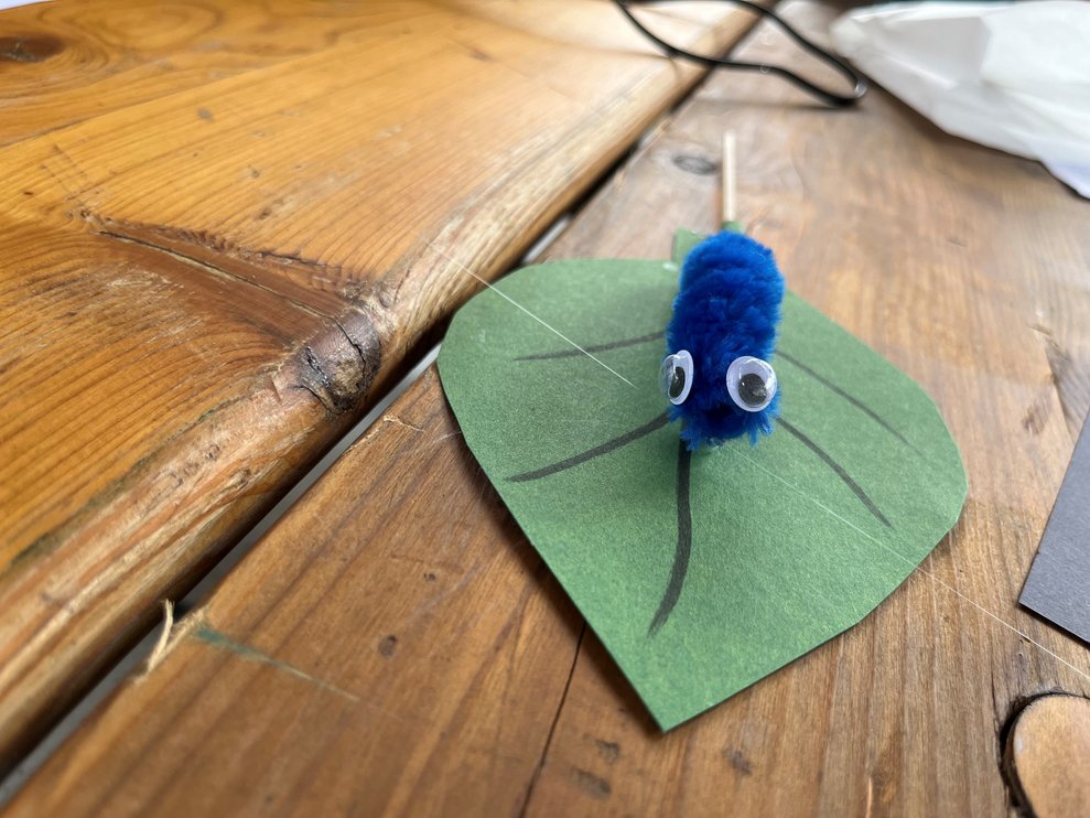 Eine Raupe aus Pfeifenreiniger auf einem Blatt.