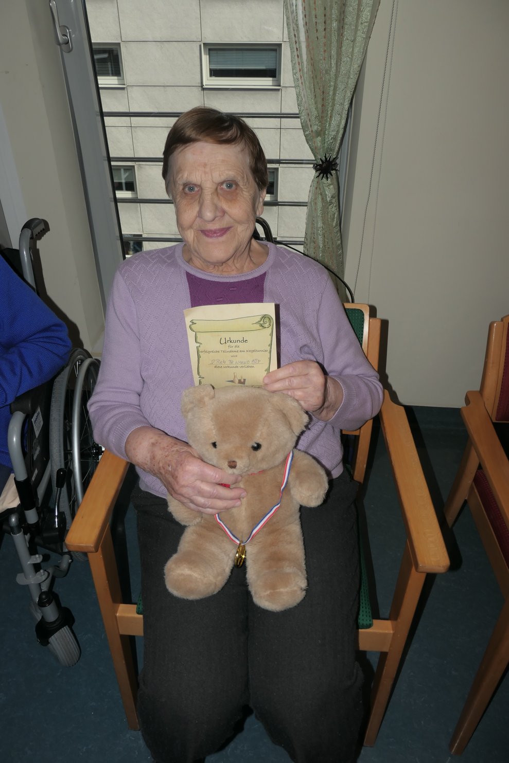Eine Dame mit Teddy, Medaille und Urkunde.