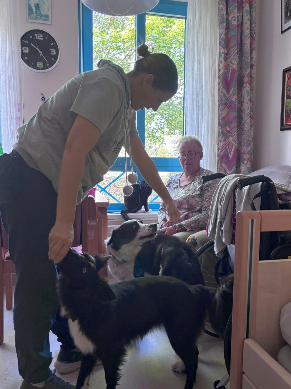 Frau (Frauerl) mit zwei Hunden. Bewohnerin mit Katze im Hintergrund.