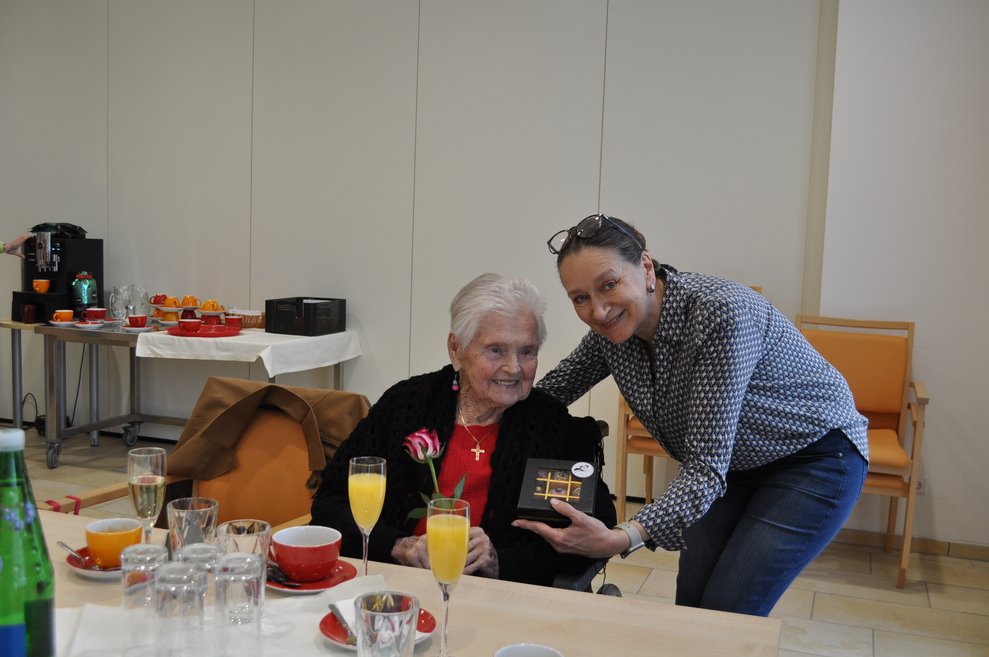 eine Frau überreicht einer älteren Dame Pralinen
