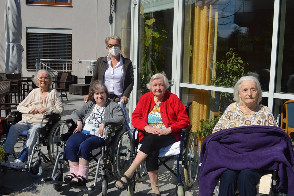 Bewohnerinnen sitzen draußen.