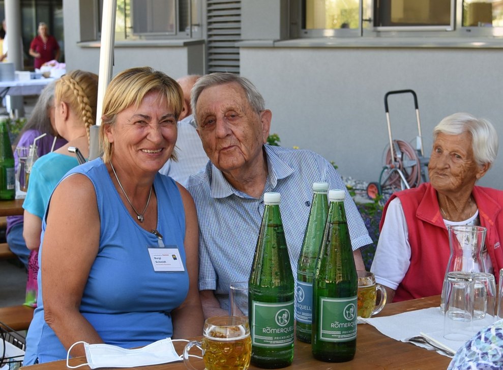 Eine Frau sitzt neben BewohnerInnen.