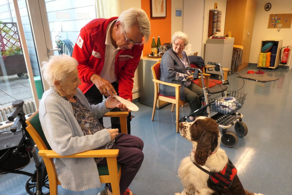Der Besitzer überreicht einer Bewohner ein Spielzeug des Hundes.