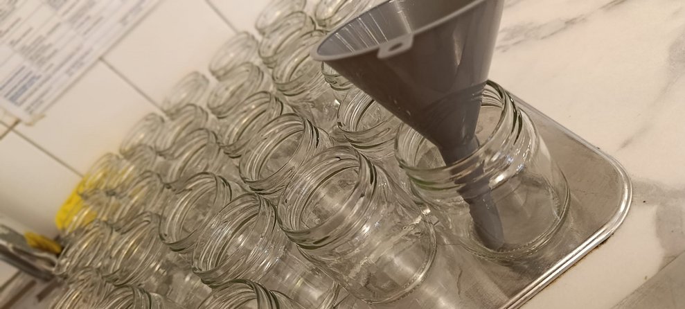 Leere Marmeladegläser. Ein Marmeladeglas mit Trichter. 