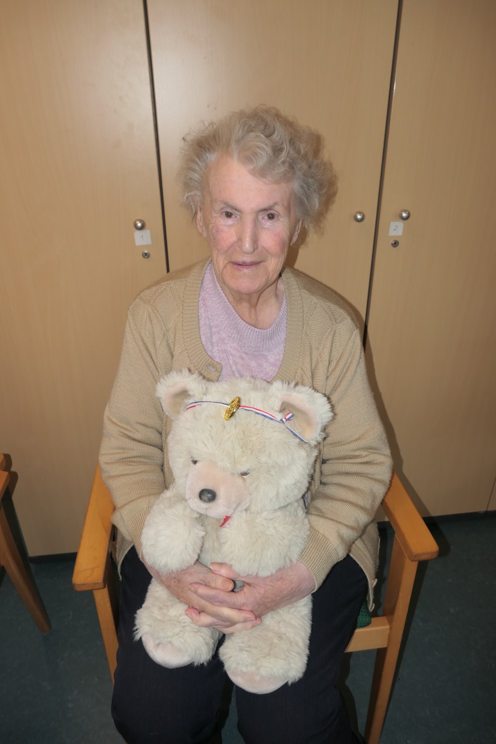 Eine Dame mit Teddy und Medaille.