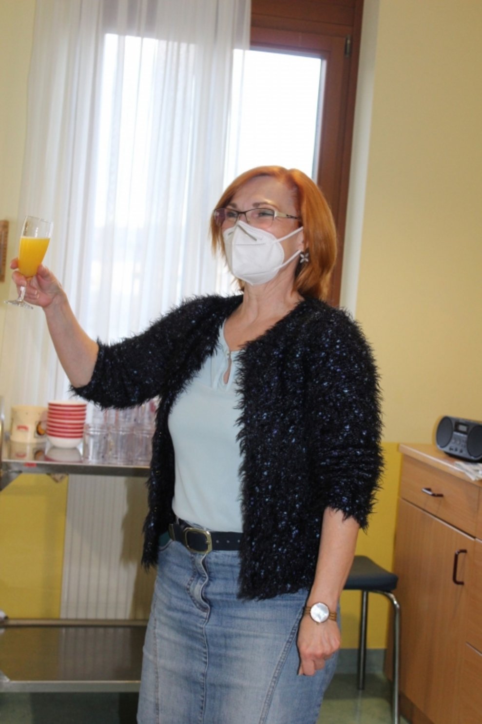 Die Direktorin hält ein Glas in der Hand.