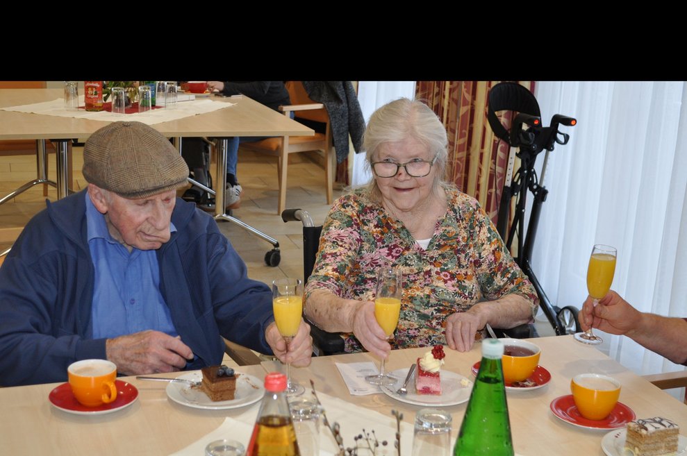 ein älterer Herr und eine ältere Frau mit Sekt Orange
