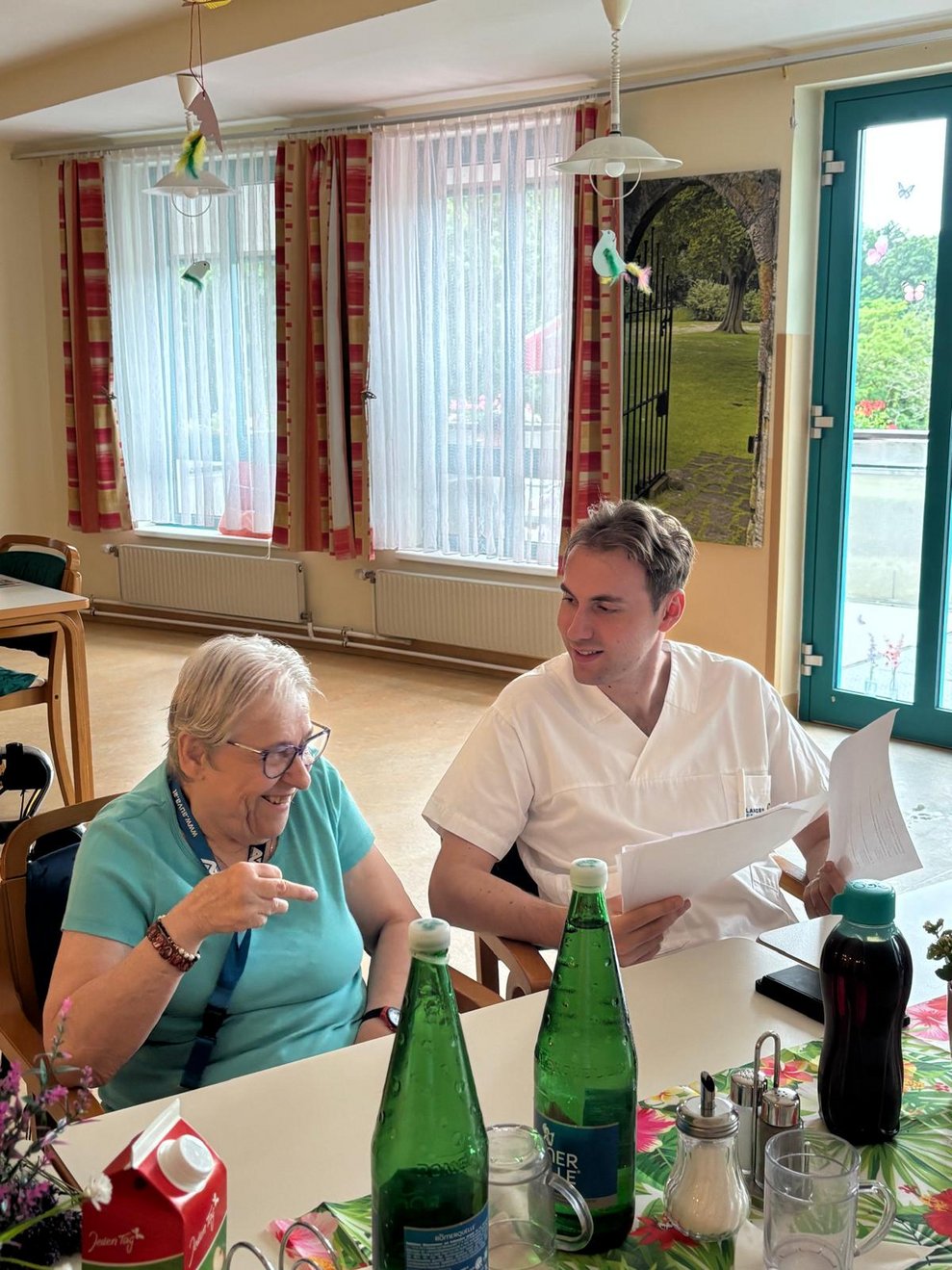 Bewohnerin und Mann (Aushilfskraft) lachen.
