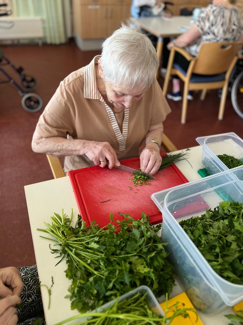 Frau Konrath beim Kräuter schneiden