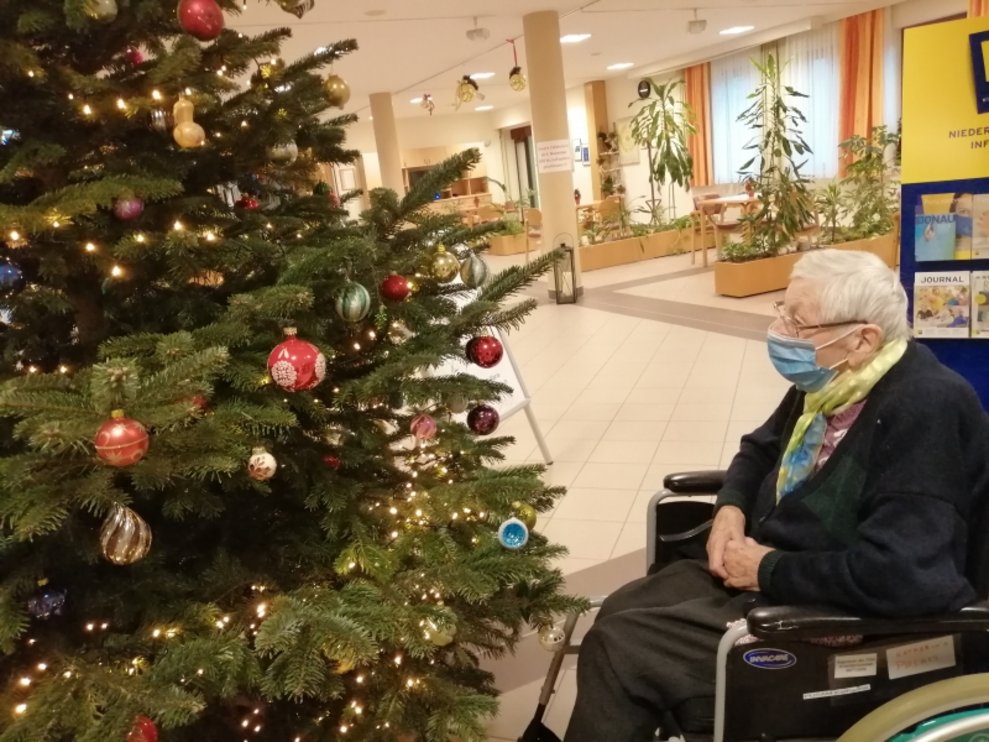 Ein Bewohner sitzt beim Christbaum.