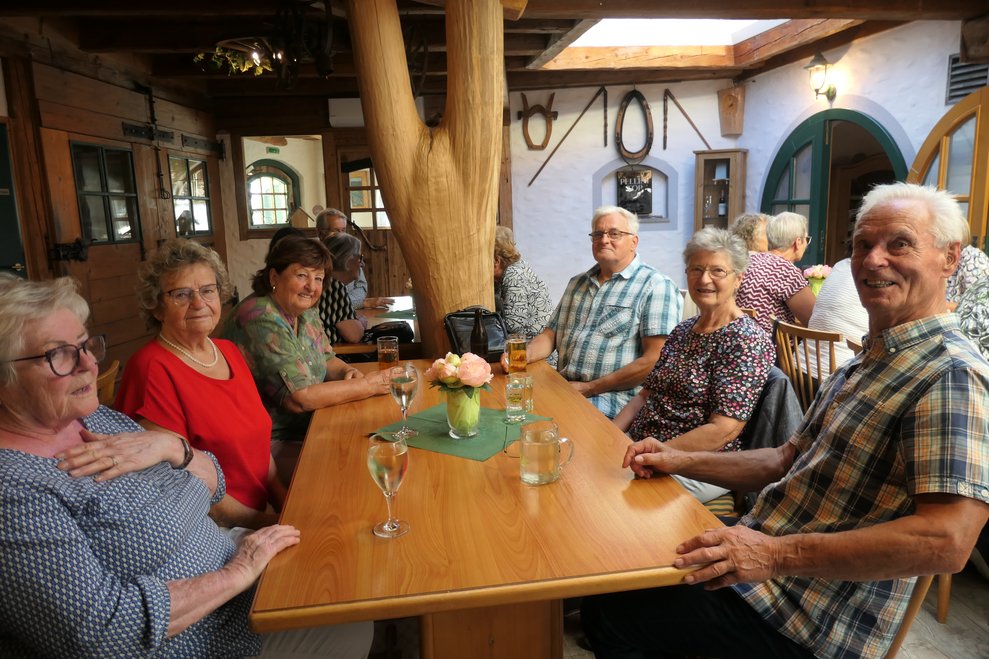 Damen und Herren beim Heurigen sitzend
