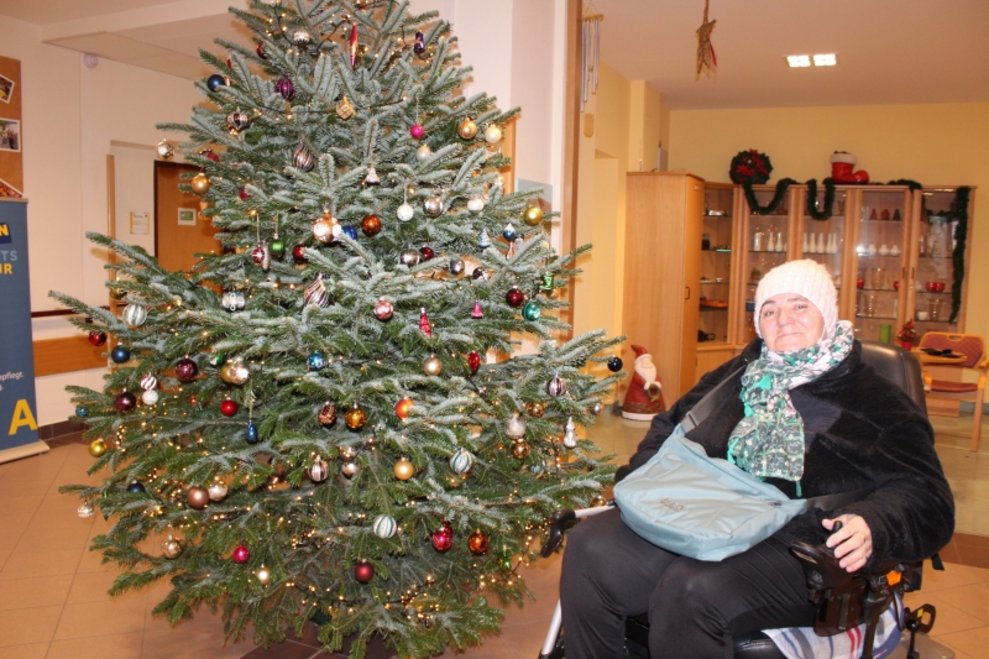 Eine Bewohnerin sitzt beim Christbaum.