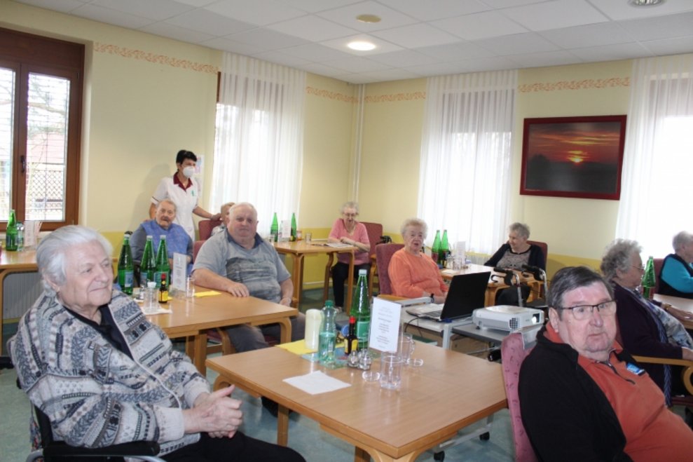 BewohnerInnen sitzen bei Tischen.