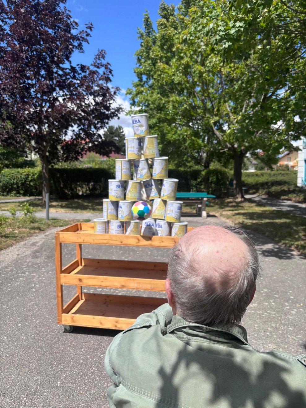 Bewohner beim Dosenschießen. Ball fliegt Rchtung Dosen.