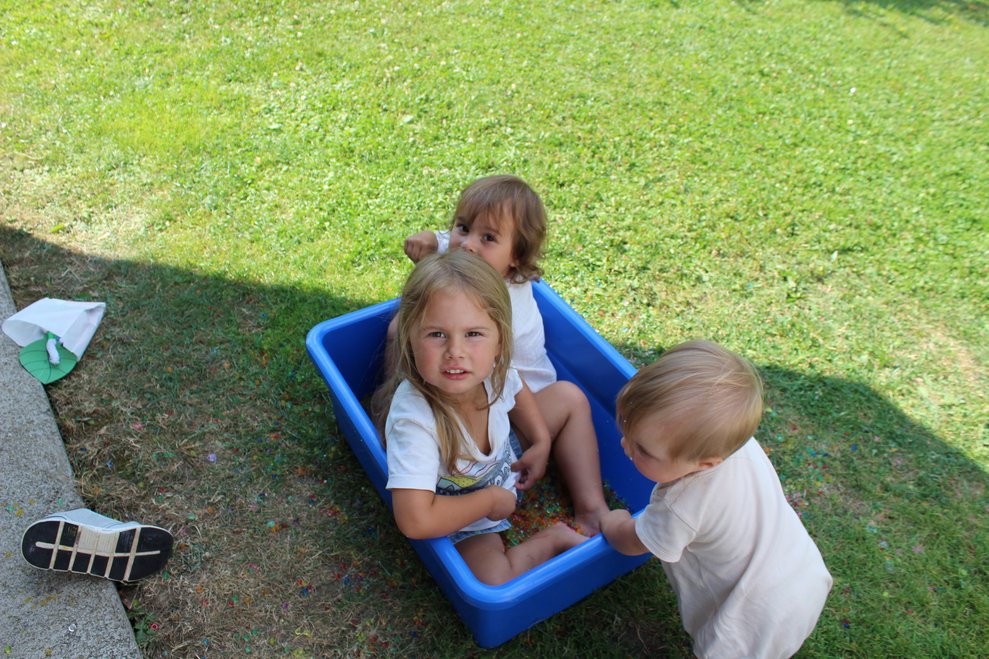 Kinder sitzen zur Abkühlung in dem kleinen Becken mit Aquaperlen.