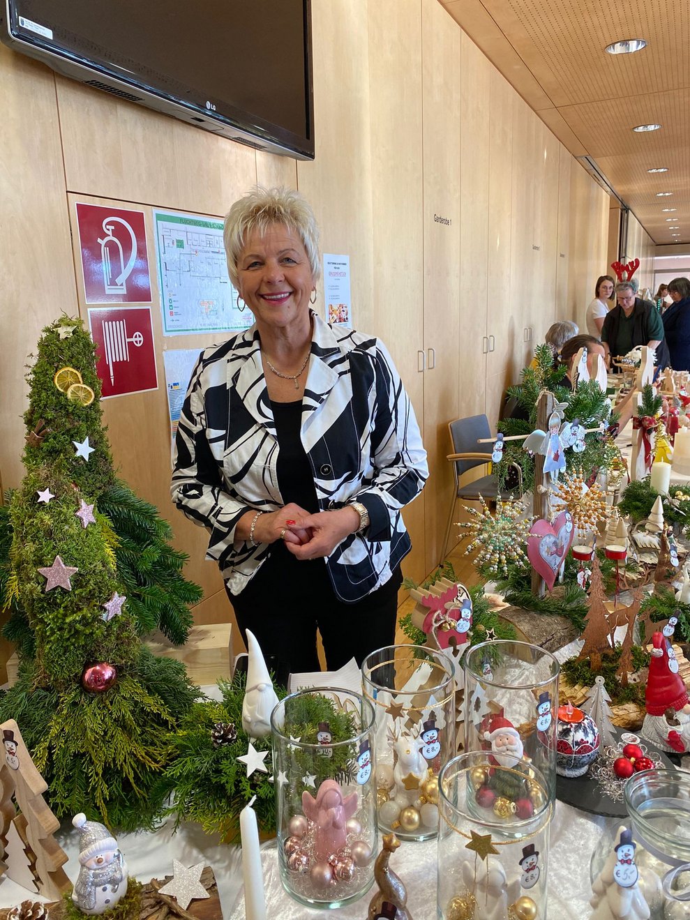 Dame steht vor ihrem Stand mit Wichteln 