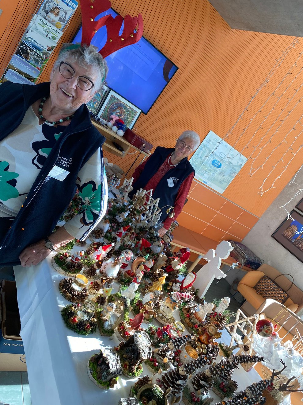 ehrenamtliche Mitarbeiterinnen stehen beim Tisch mit weihnachtlichen Bastelsachen