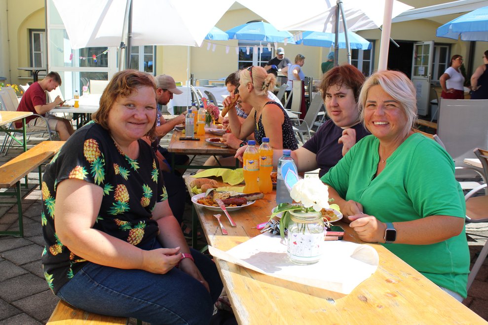 Mehrere Personen sitzen an einem Tisch und essen Mittagessen.