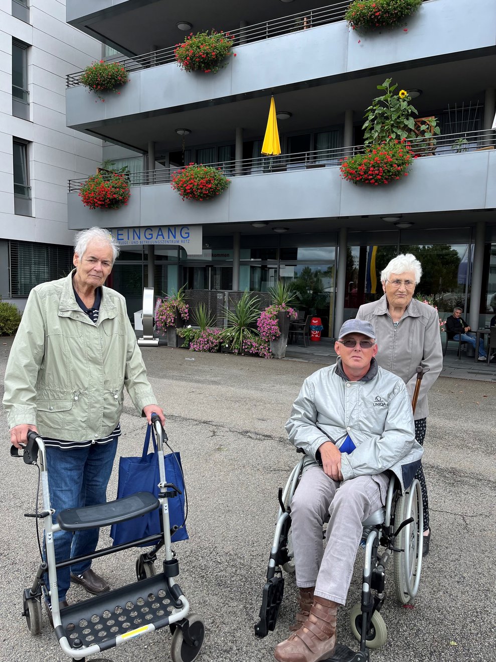 vor dem Haus stehend drei Personen