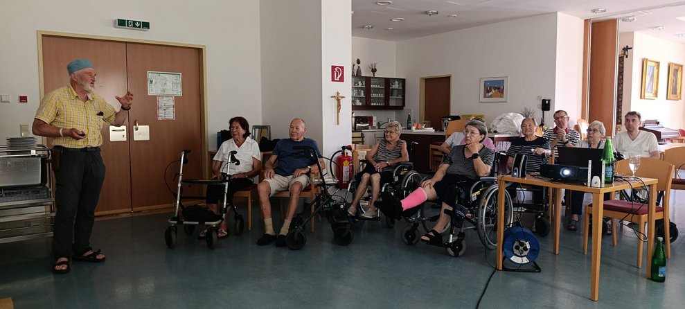 Ehrenamtlich Tätiger hält einen Vortrag. Viele sitzende Personen.