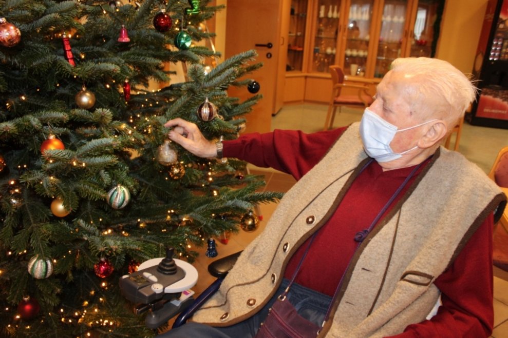 Ein Bewohner schmückt den Christbaum.