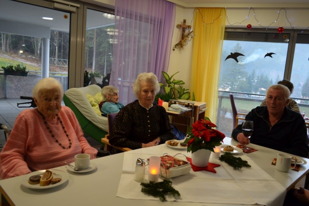 BewohnerInnen sitzen bei einem Tisch, auf dem eine Kerze steht.