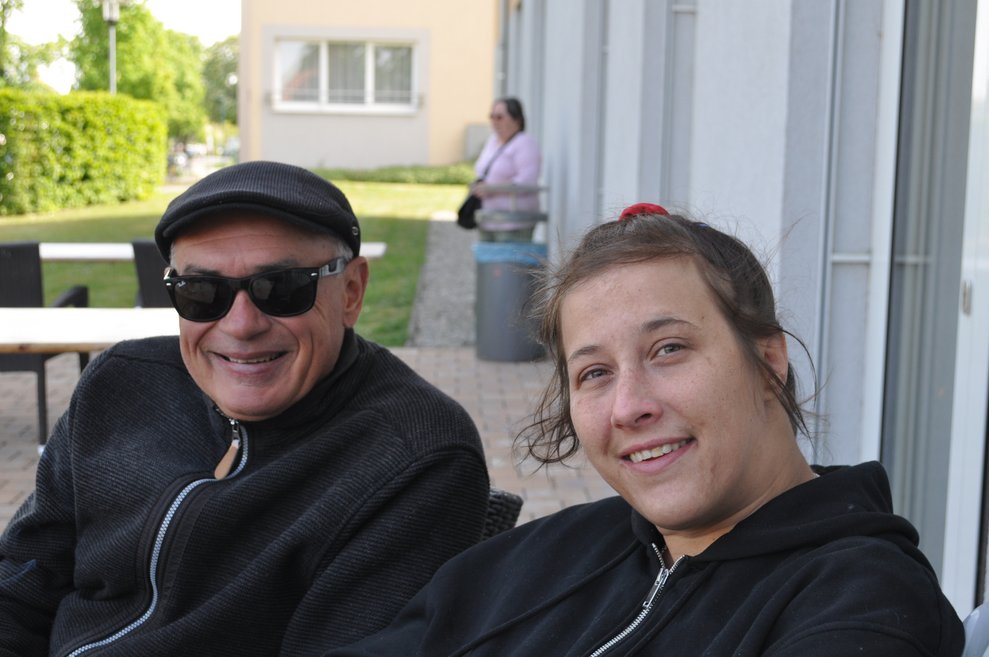 ein Angehöriger und eine junge Bewohnerin sitzen im Garten