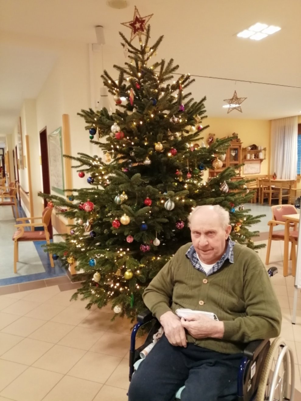 Ein Bewohner sitzt beim Christbaum.