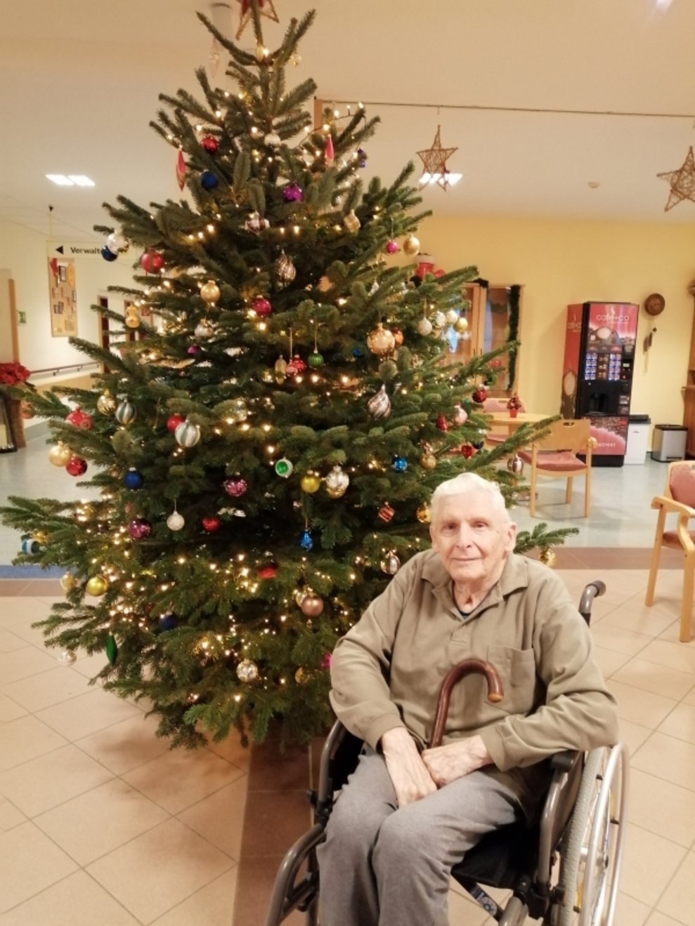 Ein Bewohner sitzt beim Christbaum.