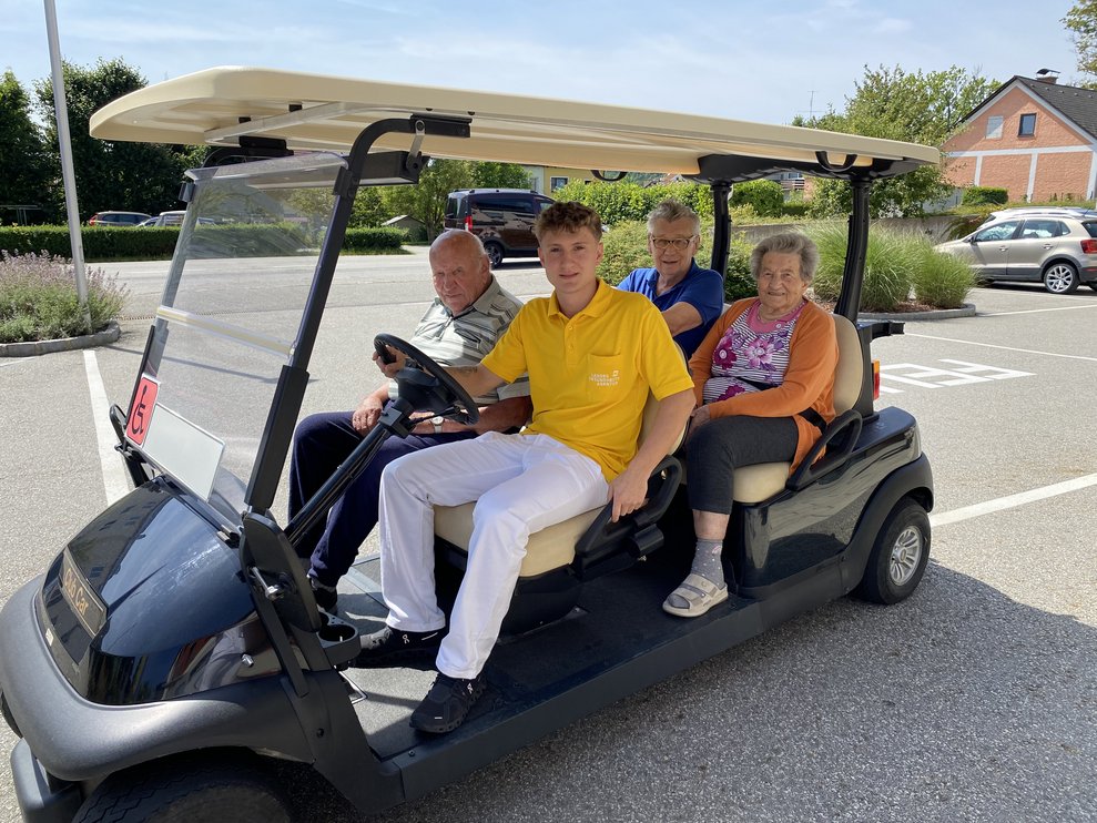 Zivi Fabian bringt einige Bewohnerinnen und Bewohner mit dem Golfcar zur Hafenbar.