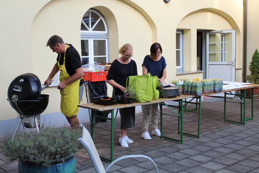 3 Personen bereiten Essen und Trinken vor.