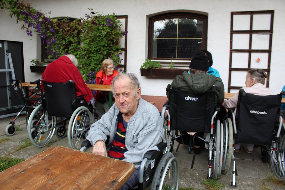 Bewohner im Rollstuhl sitzt beim Tisch