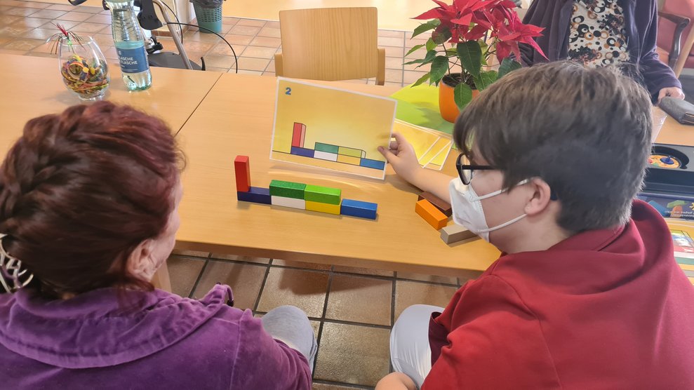 Mit bunten Holzblöcken versuchen die Bewohnerinnen und Bewohner die Anordnung auf den Bildern nachzubauen.