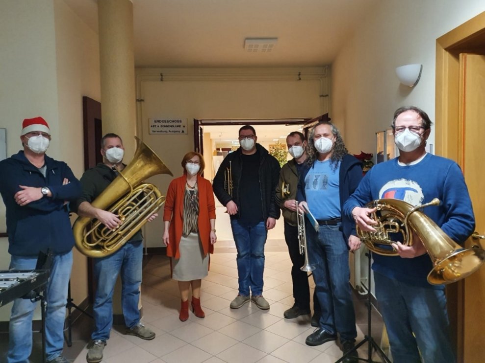 Die Direktorin steht neben Musikanten.
