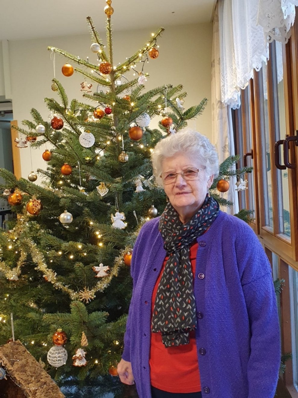 Eine Bewohnerin steht beim Christbaum.
