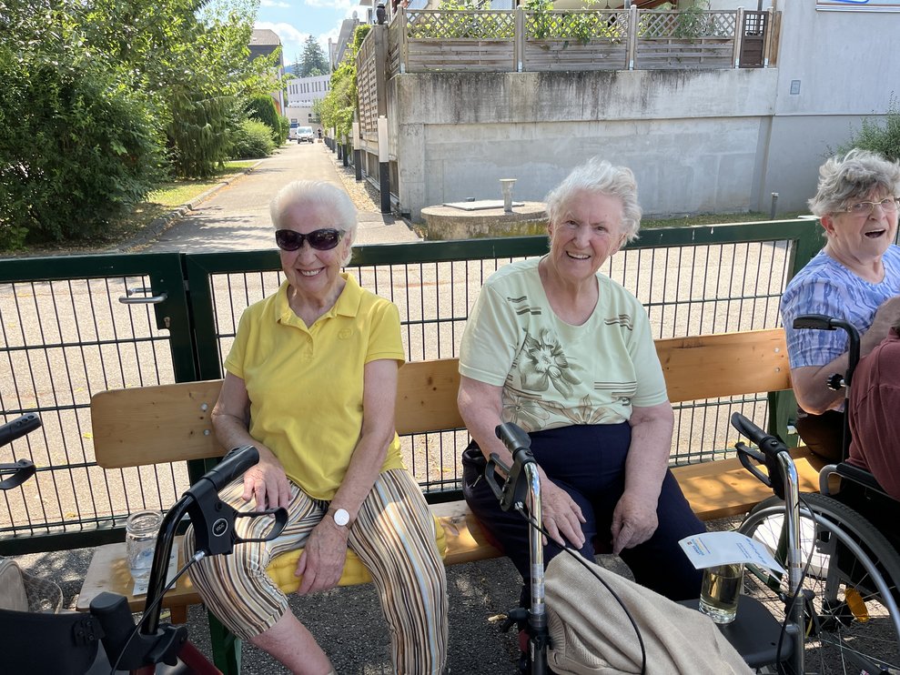 2 Bewohnerinnen sitzen auf der Heurigenbank in der Sonne