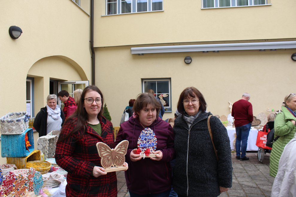 Drei Damen stehen nebeneinander und halten ein Dekoprodukt in der Hand.
