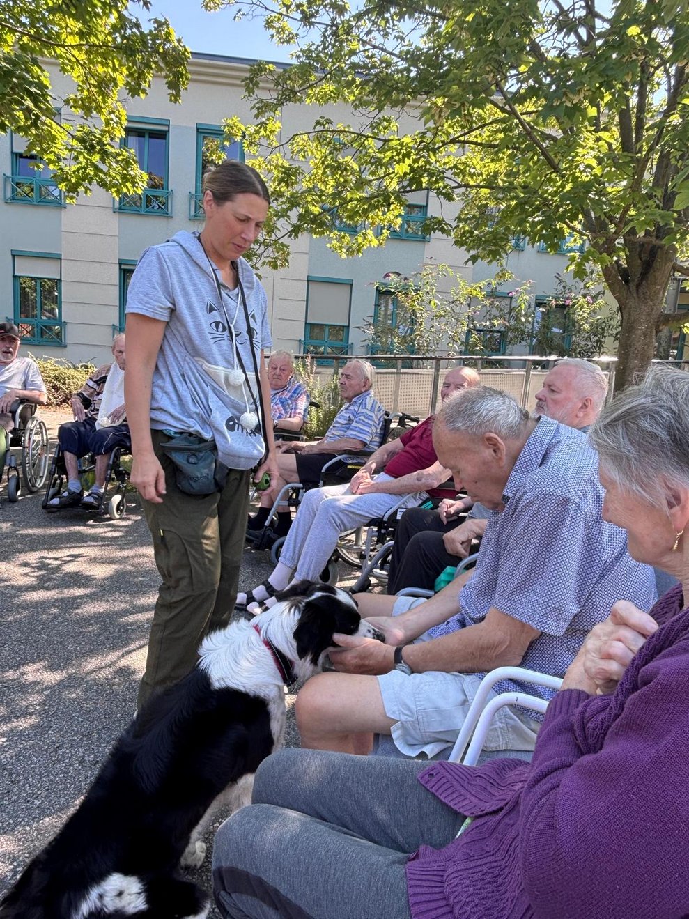 Bewohner gibt Hund Leckerli. Frau steht.