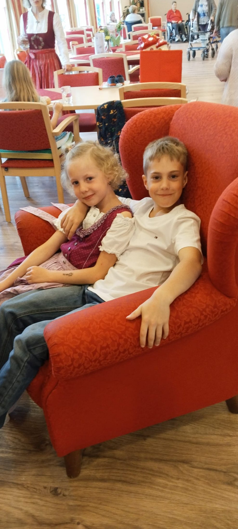 Ein Mädchen und ein Bub auf einem Stuhl.