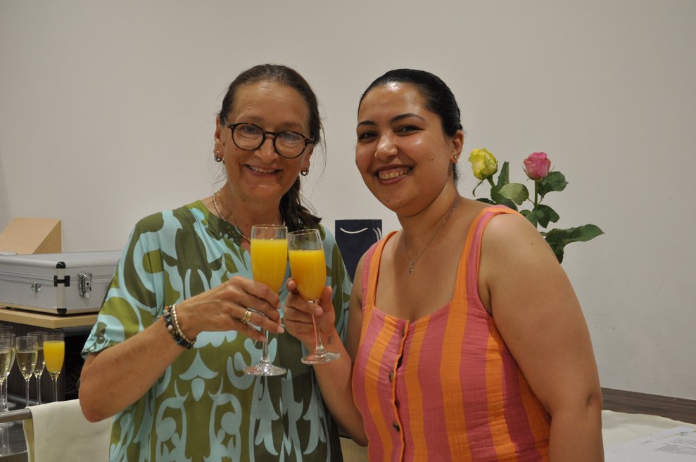zwei Frauen stoßen mit Sekt orange an