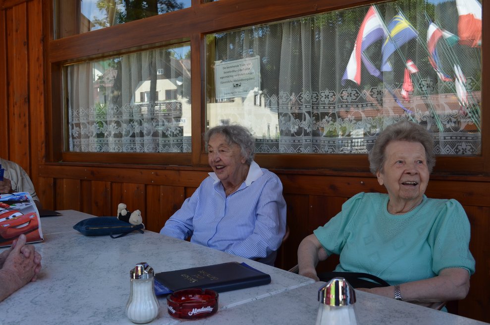 Zwei Bewohnerinnen sitzen an einem Tisch auf der Terasse 