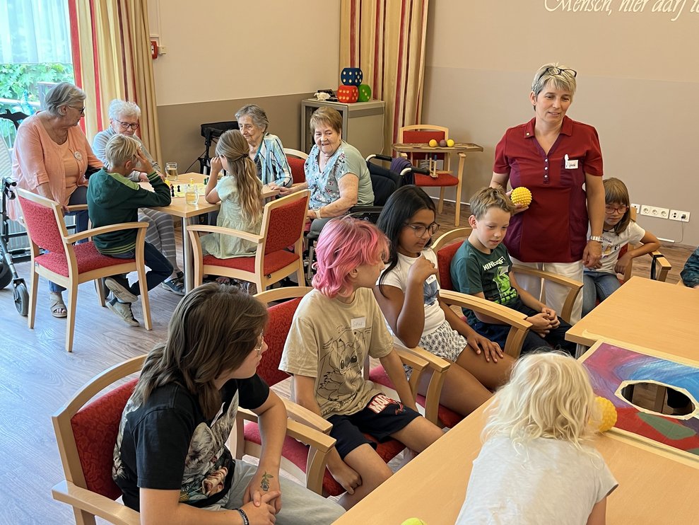 BewohnerInnen mit Kindern sitzen im Festsaal