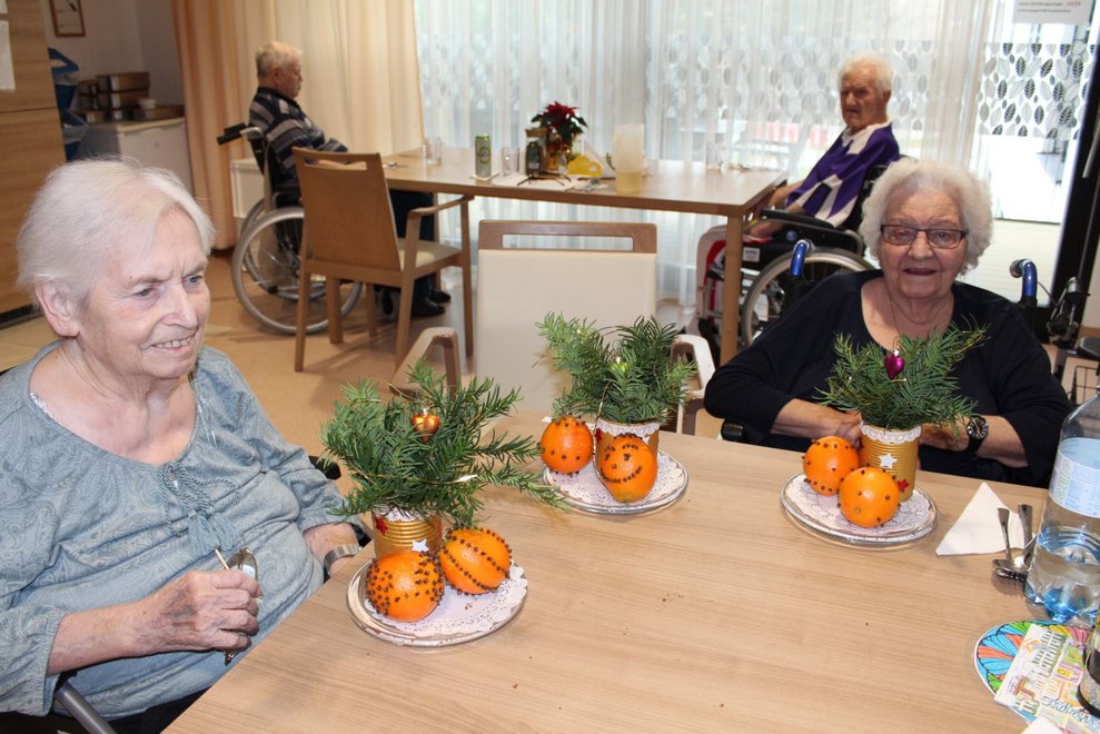 Zwei Bewohnerinnen mit dekorierten Orangen.
