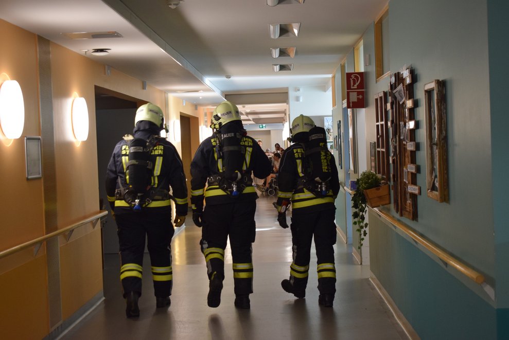 Drei Feuerwehrmänner von hinten.