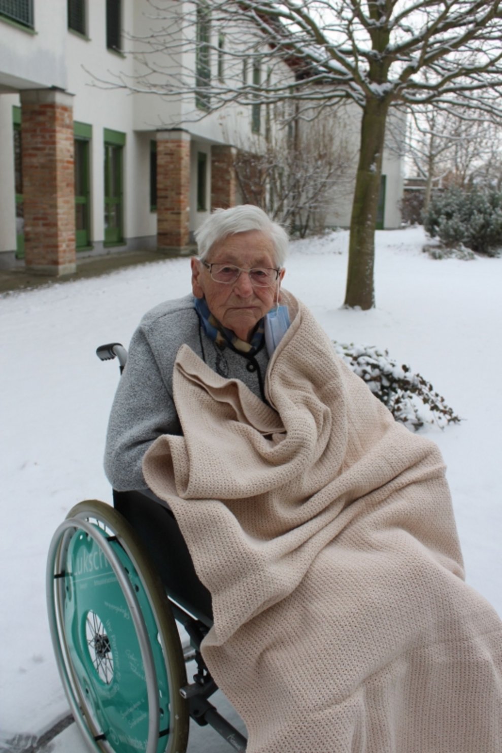 Eine Bewohnerin sitzt draußen beim Schnee.
